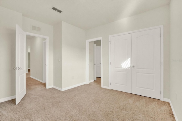 unfurnished bedroom featuring light colored carpet and a closet