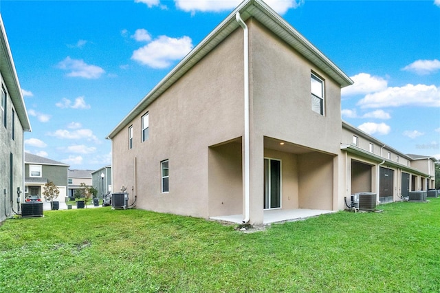 back of house with central AC unit, a lawn, and a patio