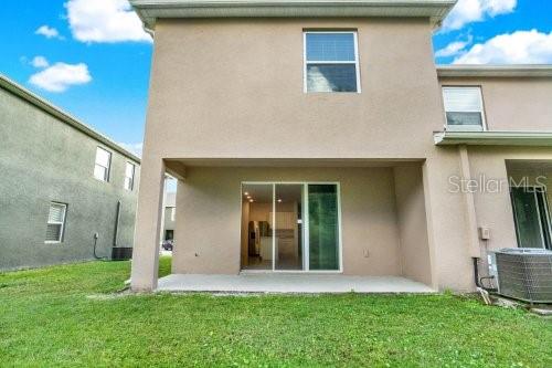 back of property featuring a lawn, cooling unit, and a patio area