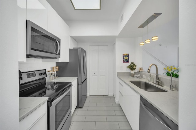 kitchen featuring light stone countertops, appliances with stainless steel finishes, sink, white cabinetry, and hanging light fixtures