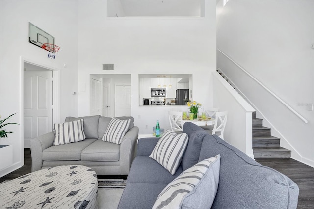 living room featuring a towering ceiling and dark wood-type flooring