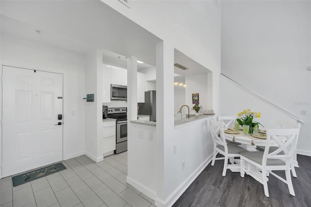 kitchen featuring sink, a notable chandelier, appliances with stainless steel finishes, white cabinets, and light wood-type flooring