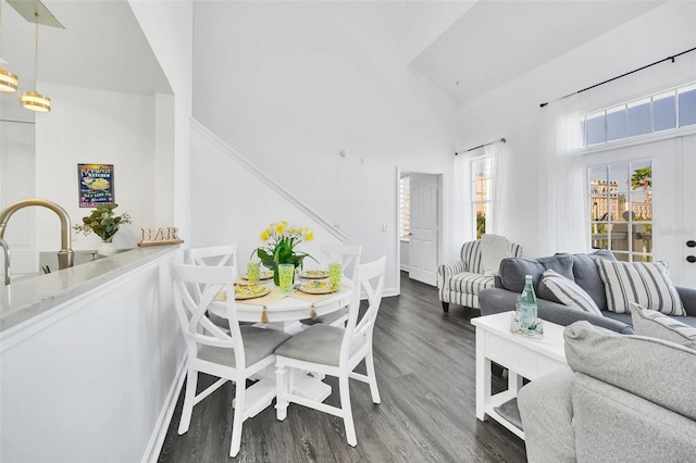 dining space with high vaulted ceiling and dark wood-type flooring