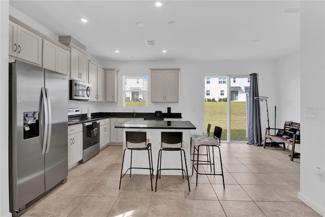 kitchen with a kitchen breakfast bar, plenty of natural light, appliances with stainless steel finishes, and a center island