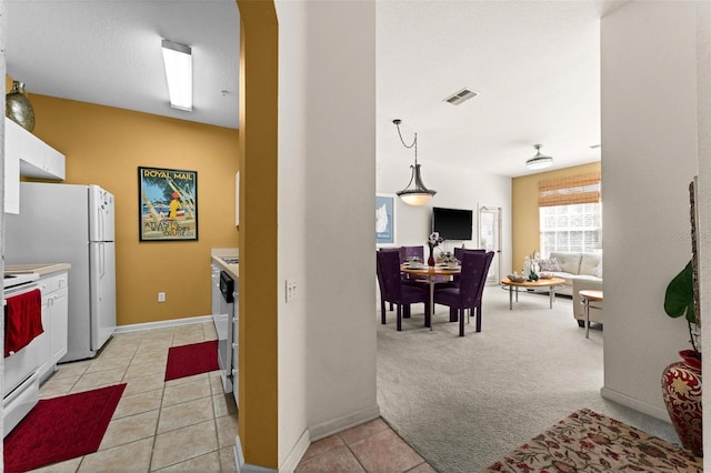 kitchen featuring pendant lighting, white cabinets, light colored carpet, stove, and white refrigerator