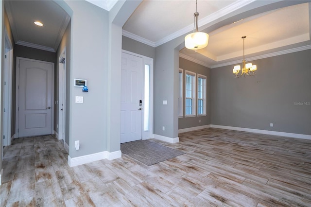 foyer with an inviting chandelier, light hardwood / wood-style flooring, and ornamental molding