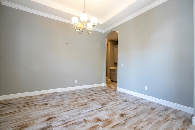 spare room featuring light hardwood / wood-style floors, ornamental molding, and an inviting chandelier