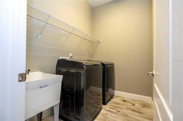 laundry room with washer and clothes dryer, light hardwood / wood-style floors, and sink