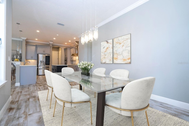 dining room featuring light hardwood / wood-style flooring, ornamental molding, and sink