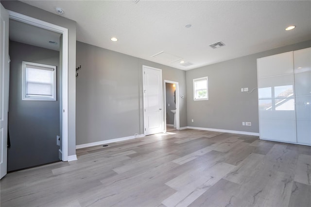 spare room featuring a textured ceiling and light hardwood / wood-style flooring