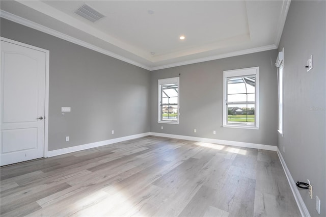 unfurnished room with a raised ceiling, light hardwood / wood-style floors, and ornamental molding