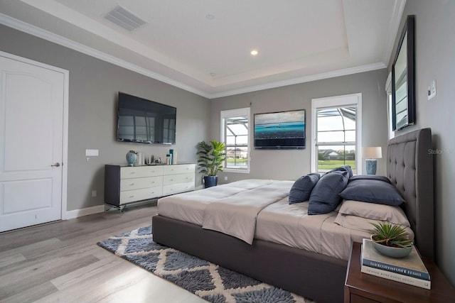 bedroom featuring ornamental molding, a tray ceiling, and light hardwood / wood-style flooring