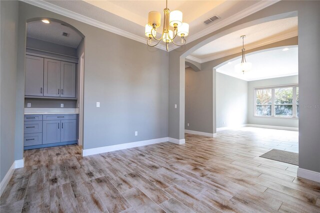 unfurnished dining area featuring a notable chandelier, light hardwood / wood-style floors, and ornamental molding