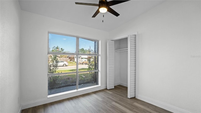 unfurnished bedroom featuring a closet, lofted ceiling, wood-type flooring, and ceiling fan