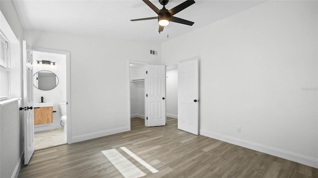 unfurnished bedroom featuring a spacious closet, hardwood / wood-style flooring, and ensuite bathroom