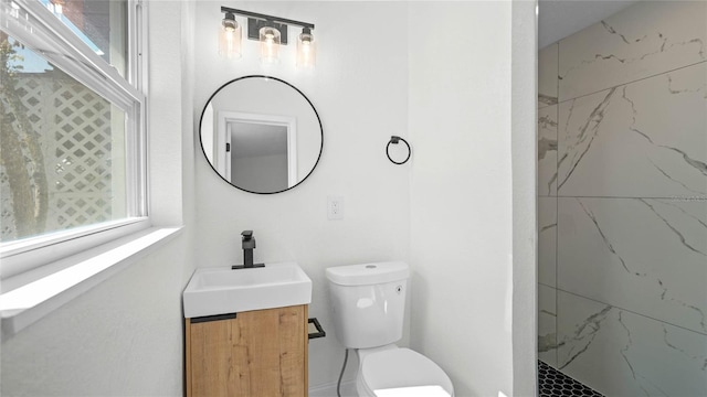 bathroom featuring toilet, vanity, and a tile shower