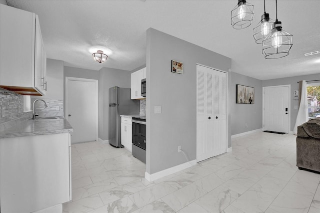 kitchen featuring appliances with stainless steel finishes, tasteful backsplash, sink, white cabinetry, and hanging light fixtures