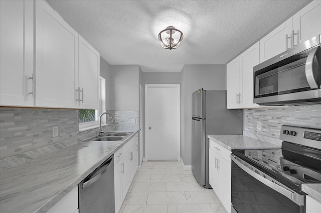 kitchen with sink, a textured ceiling, tasteful backsplash, white cabinetry, and stainless steel appliances