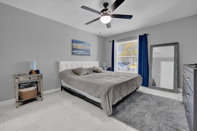 bedroom with ceiling fan and a textured ceiling