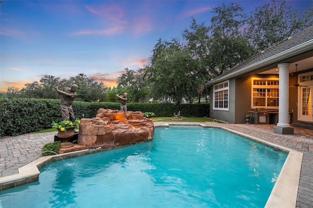 pool at dusk featuring a patio area and pool water feature