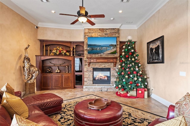 living room with a stone fireplace, crown molding, ceiling fan, and light tile patterned floors