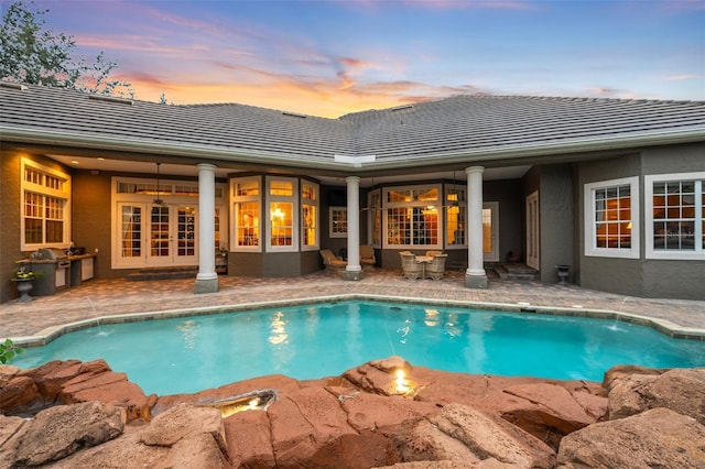 pool at dusk featuring an outdoor kitchen