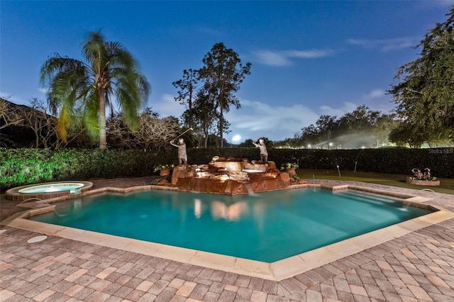 pool at dusk featuring an in ground hot tub