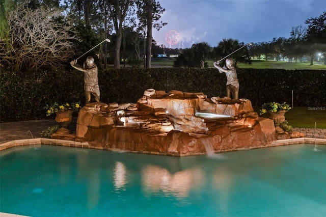 pool at dusk featuring pool water feature