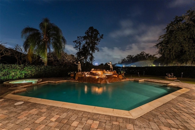 pool at dusk with an in ground hot tub and a patio