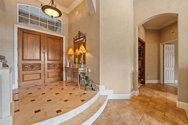 foyer entrance featuring a towering ceiling and crown molding