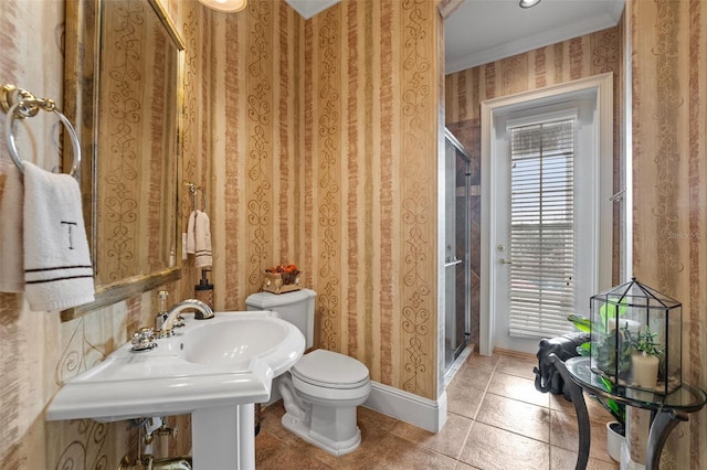 bathroom featuring tile patterned flooring, toilet, a shower with shower door, and crown molding