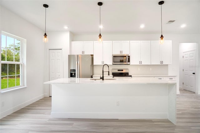 kitchen featuring white cabinets, appliances with stainless steel finishes, sink, and an island with sink