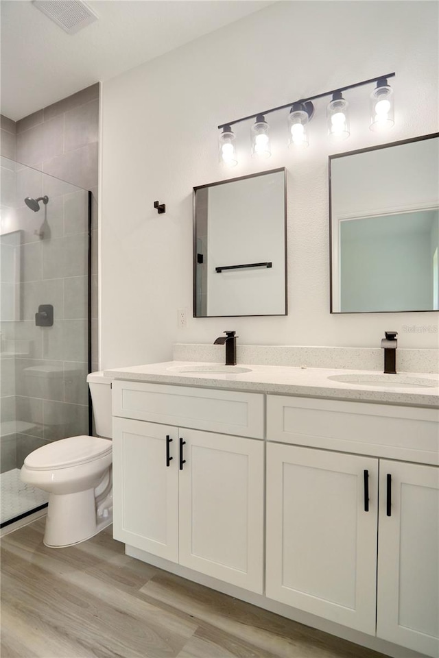 bathroom featuring vanity, hardwood / wood-style flooring, toilet, and a shower with shower door