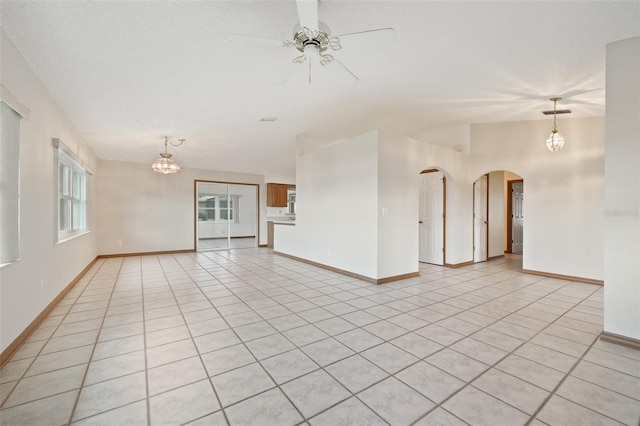 unfurnished room with ceiling fan with notable chandelier, light tile patterned floors, and lofted ceiling