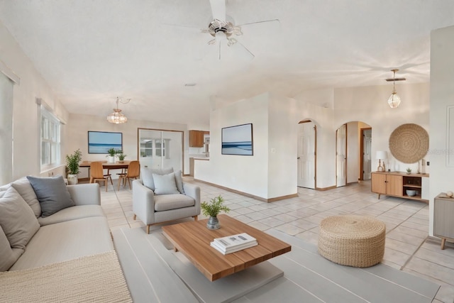 tiled living room featuring ceiling fan with notable chandelier