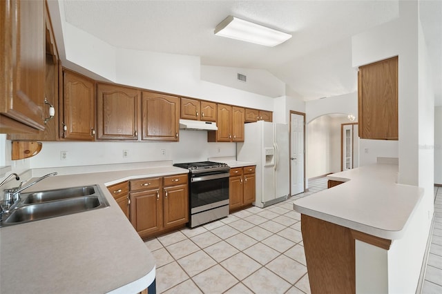 kitchen featuring white fridge with ice dispenser, sink, stainless steel range oven, kitchen peninsula, and lofted ceiling