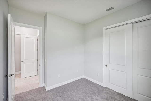 unfurnished bedroom featuring light carpet and a closet