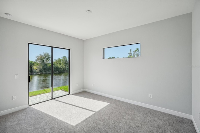 carpeted empty room featuring a water view