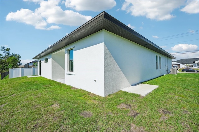 view of side of property featuring central air condition unit and a lawn