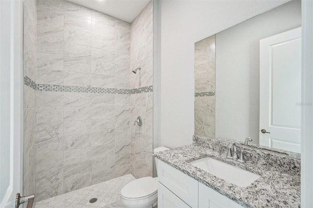 bathroom featuring toilet, vanity, and tiled shower