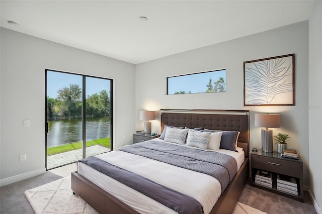 bedroom featuring access to exterior, a water view, and light colored carpet