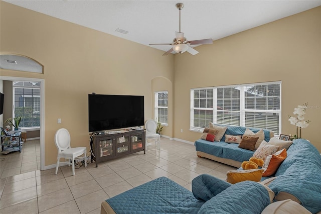 tiled living room featuring a towering ceiling, ceiling fan, and plenty of natural light