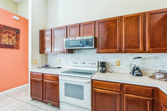 kitchen featuring backsplash, light tile patterned floors, and electric range