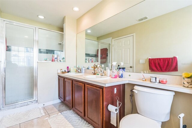 bathroom featuring toilet, vanity, tile patterned floors, and a shower with door