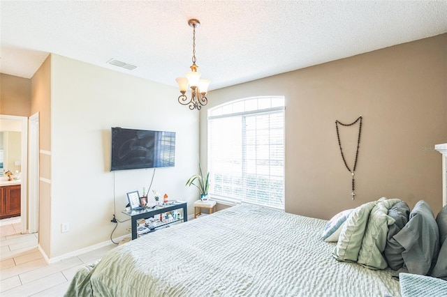 bedroom featuring connected bathroom, a textured ceiling, and a notable chandelier