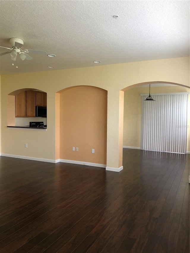 empty room with ceiling fan, dark hardwood / wood-style floors, and a textured ceiling