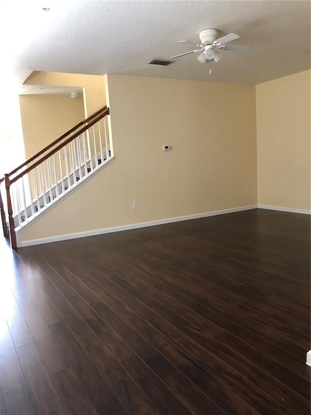 empty room with ceiling fan, dark hardwood / wood-style floors, and a textured ceiling