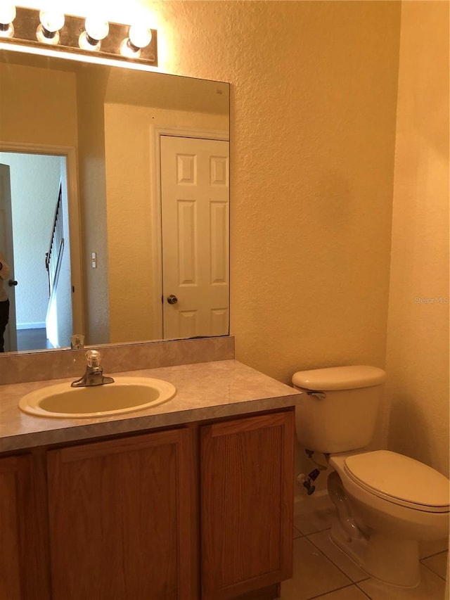 bathroom with toilet, vanity, and tile patterned flooring