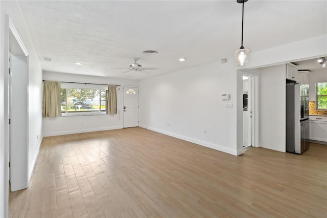 unfurnished living room featuring ceiling fan, a healthy amount of sunlight, and light hardwood / wood-style floors