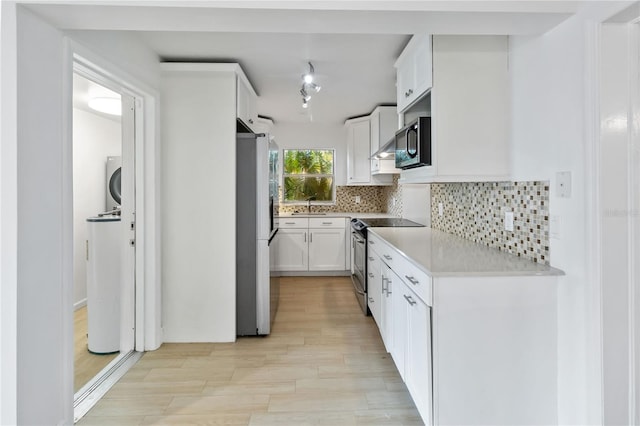 kitchen with white cabinets, decorative backsplash, light hardwood / wood-style flooring, sink, and appliances with stainless steel finishes